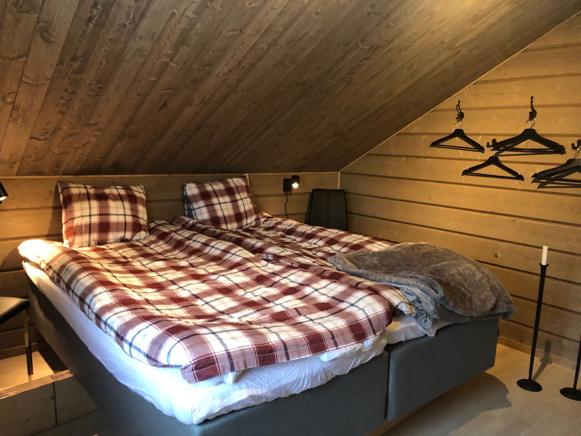 Sovrum på övervåningen med bäddad dubbelsäng under snedtak i trä