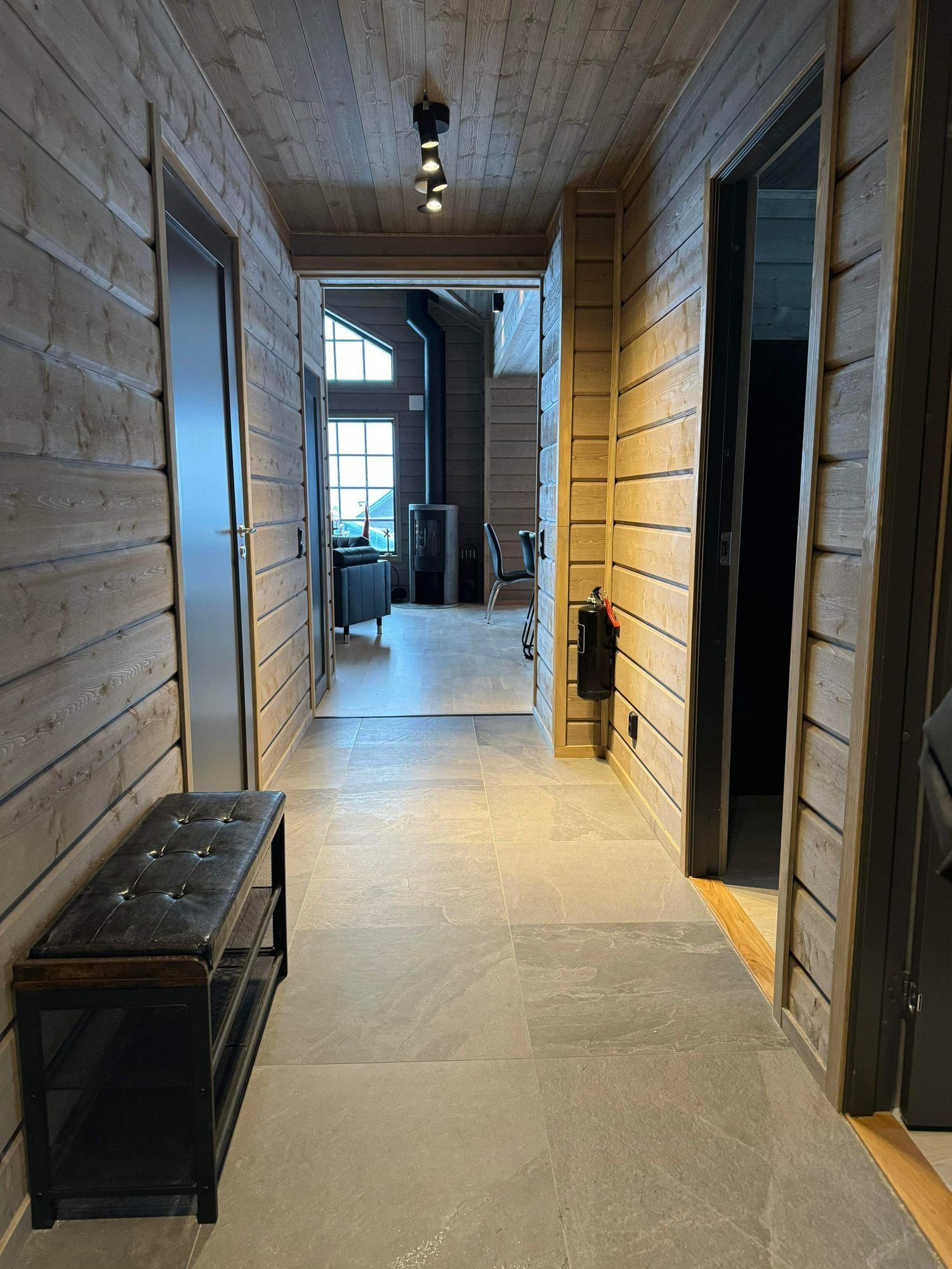 Entréhall i ljust timmer med utblick mot vardagsrummet och kaminen